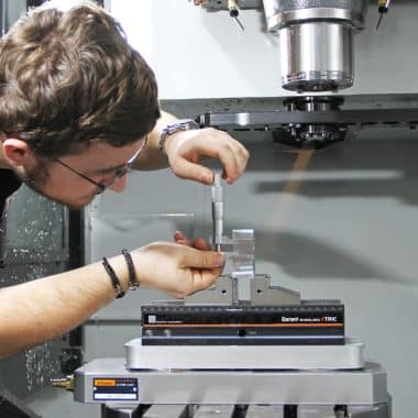 Étudiant en train de mesurer une pièce métallique dans une machine à commande numérique HAAS.