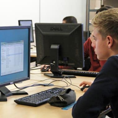 Lycéen en train de travailler devant son écran d'ordinateur dans une salle de classe