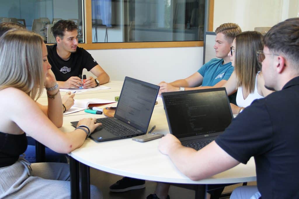 Groupe d'étudiants en train de travailler devant 2 ordinateurs portables.