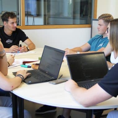 Groupe d'étudiants en train de travailler devant 2 ordinateurs portables.