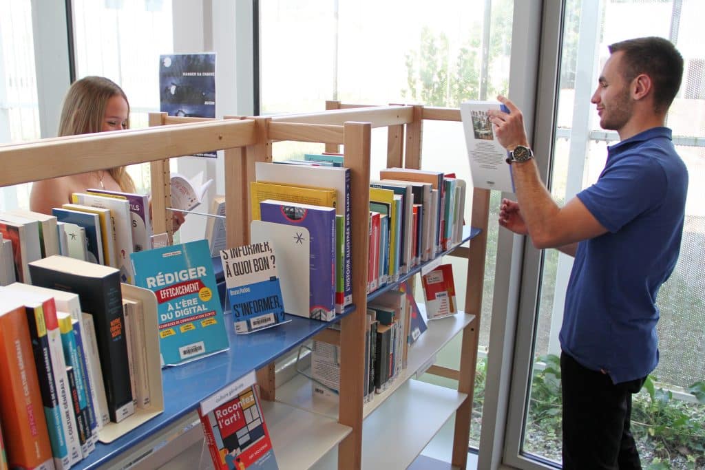 Étudiants en train de choisir des livres dans la rayonnages du centre de documentation et de ressources.