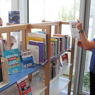 Étudiants en train de choisir des livres dans la rayonnages du centre de documentation et de ressources.