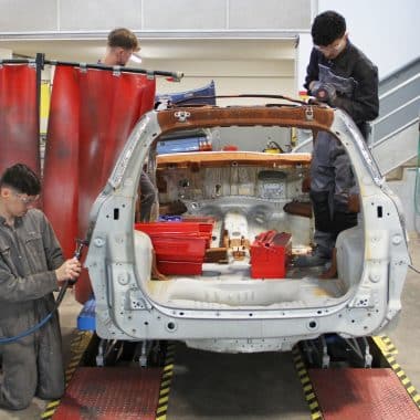 Lycéens en train de réparer la carrosserie d'une voiture dans un atelier de la Joliverie.