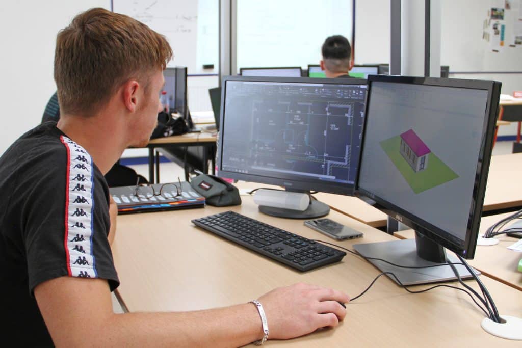 Étudiant devant son ordinateur en train de dessiner des plans d'architecture d'un bâtiment.