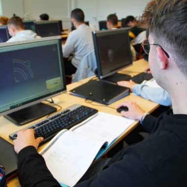 Étudiant devant son écran d'ordinateur en train de dessiner des pièces industrielles.