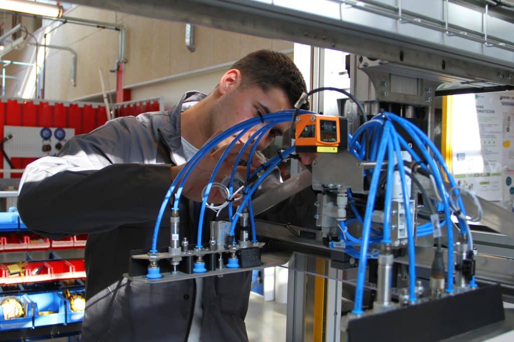 Étudiant en train de réparer une machine de production industrielle.
