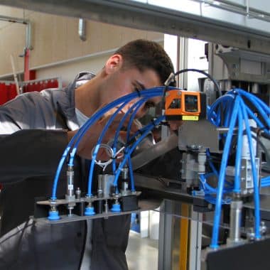 Étudiant en train de réparer une machine de production industrielle.