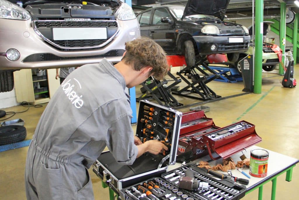 Étudiant en train de prendre un outils pour réaliser la maintenance d'un véhicule.
