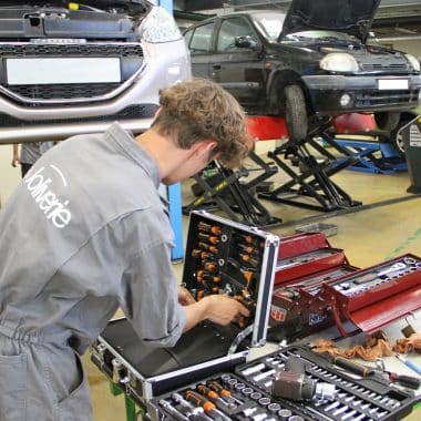 Étudiant en train de prendre un outils pour réaliser la maintenance d'un véhicule.