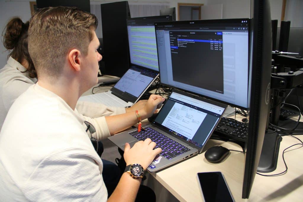 Étudiant en informatique devant plusieurs écrans d'ordinateur en train d'apprendre son cours.