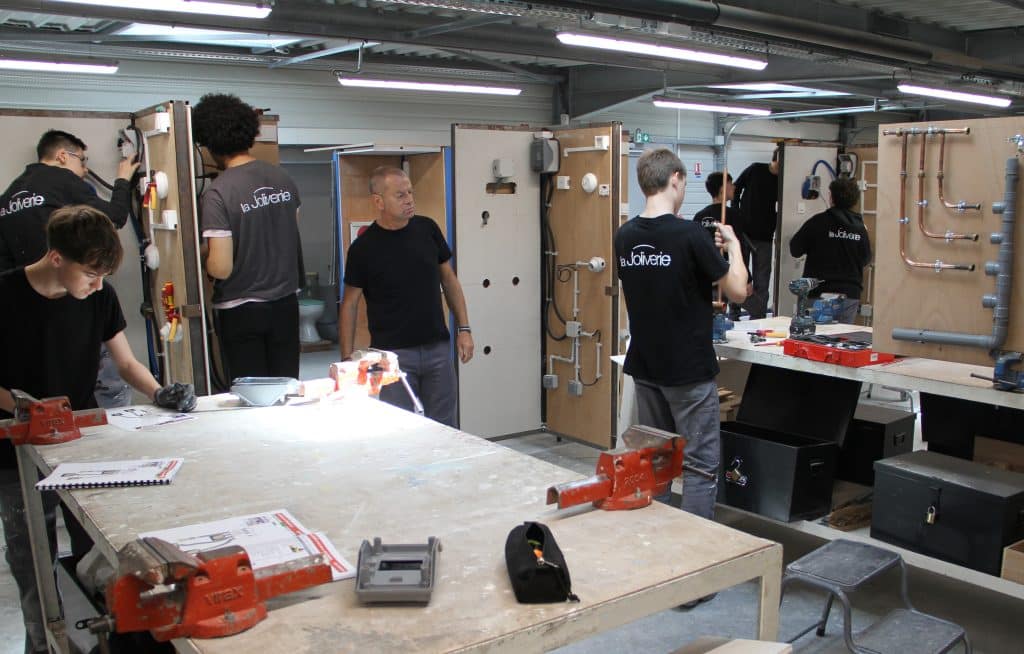 Atelier avec plusieurs élèves en train de bricoler de l'électricité et de la plomberie.