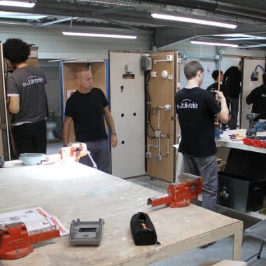 Atelier avec plusieurs élèves en train de bricoler de l'électricité et de la plomberie.