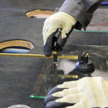 Main d'un élève en train de découper un plaque de verre.