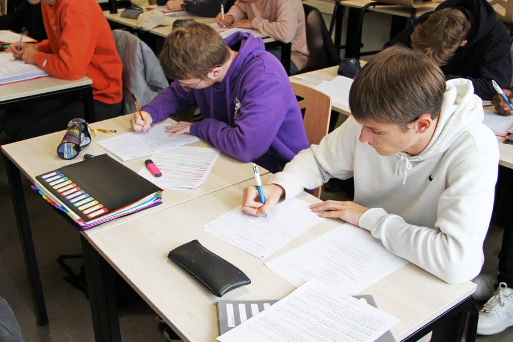 2 étudiants dans une classe en train d'écrire sur leur feuille de cours.