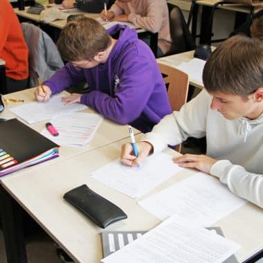 2 étudiants dans une classe en train d'écrire sur leur feuille de cours.