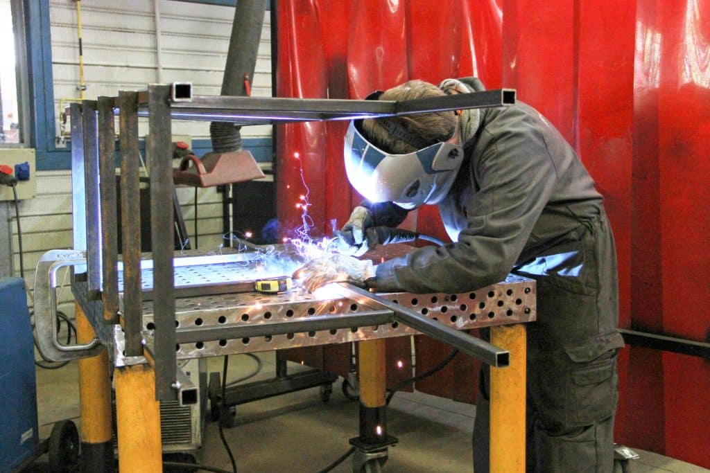Élève en train de souder une pièce métallique dans un atelier.