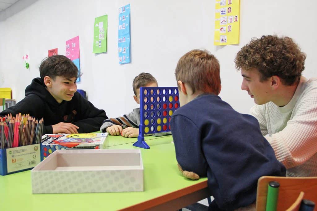 Élèves en train d'animer un atelier ludique avec des enfants dans une salle.