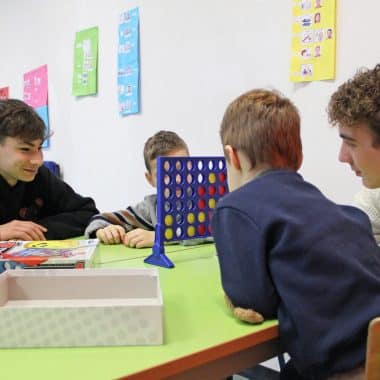 Élèves en train d'animer un atelier ludique avec des enfants dans une salle.