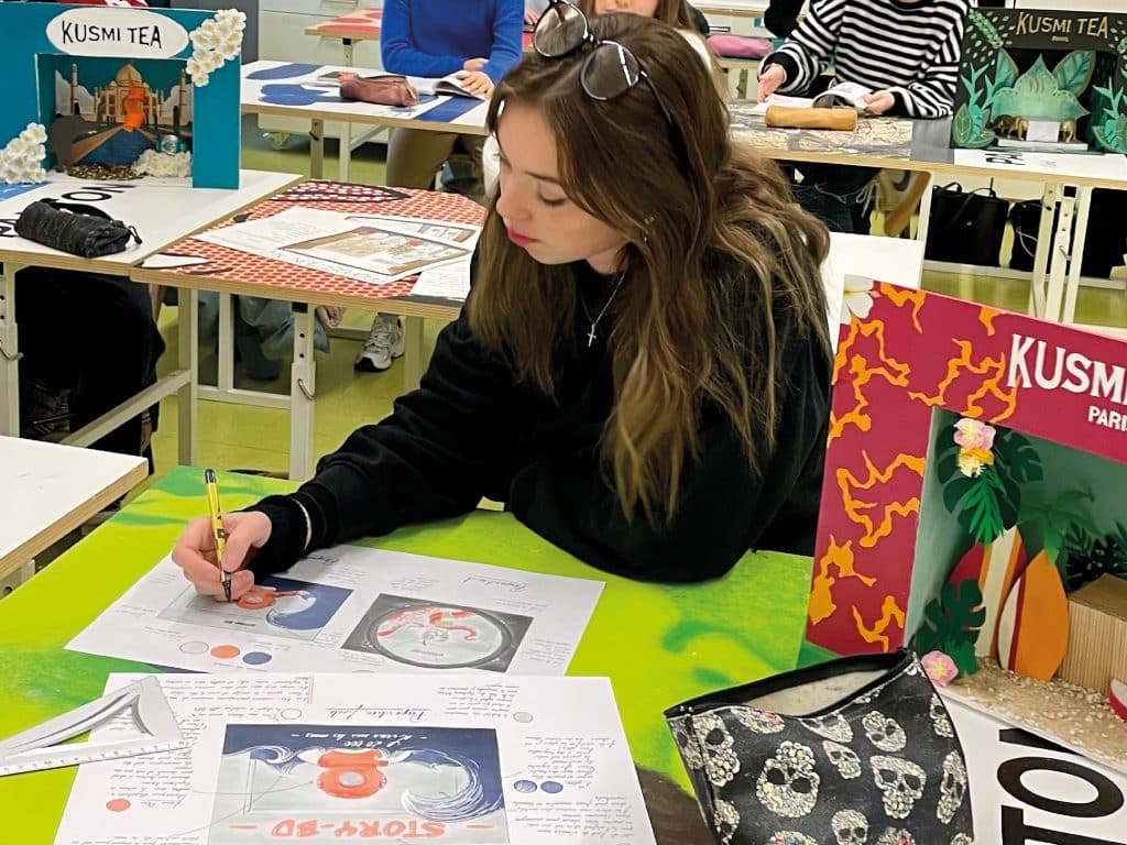 Élève en train de dessiner sur une feuille en salle de classe au Pôle des Arts Graphiques la Joliverie.