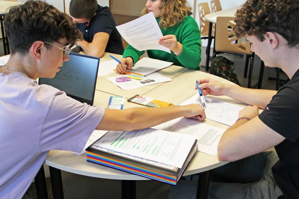 Un étudiant montre quelque chose sur la feuille d'un autre étudiant.