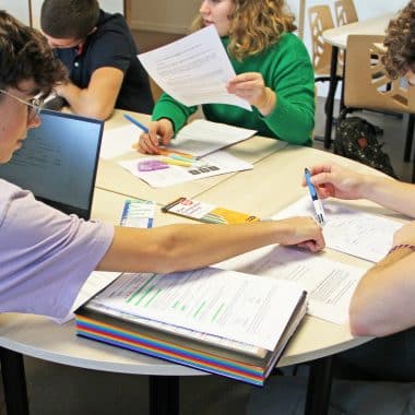 Un étudiant montre quelque chose sur la feuille d'un autre étudiant.