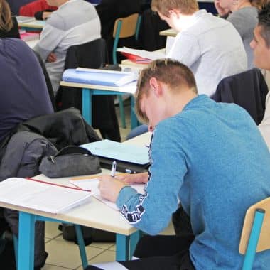 Etudiant en classe en train d'écrire sur sa feuille.