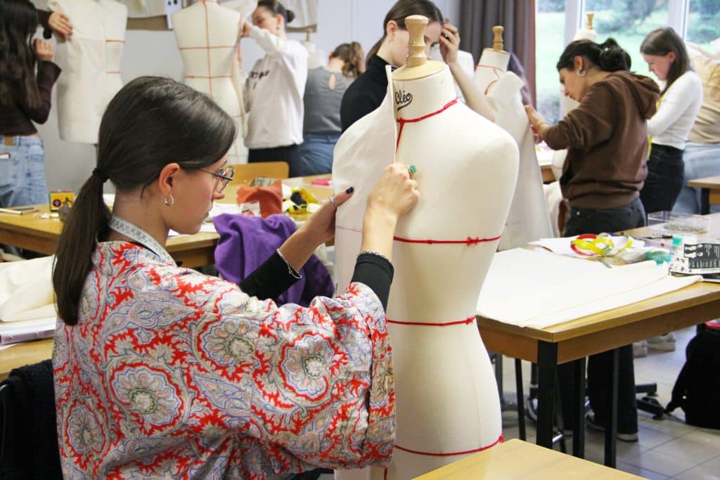 Étudiante en BTS Mode en train de confectionner une robe sur son mannequin.