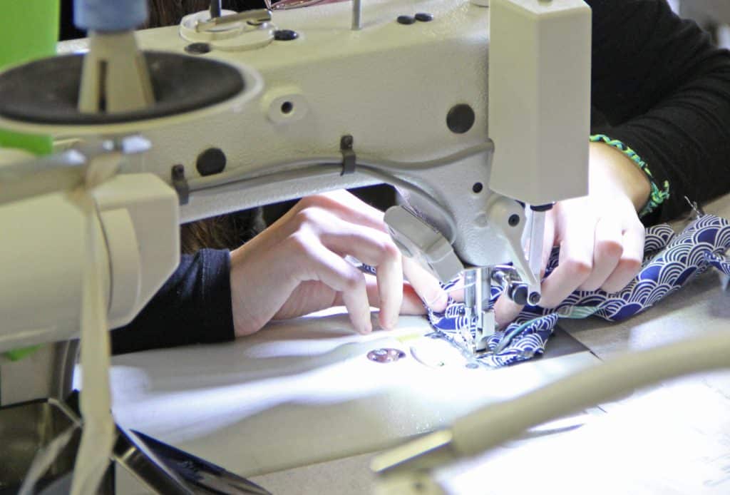 Mains d'une élève en train d'utiliser une machine à coudre.