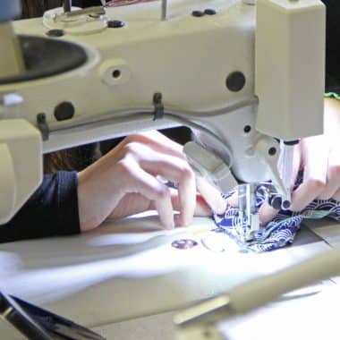 Mains d'une élève en train d'utiliser une machine à coudre.