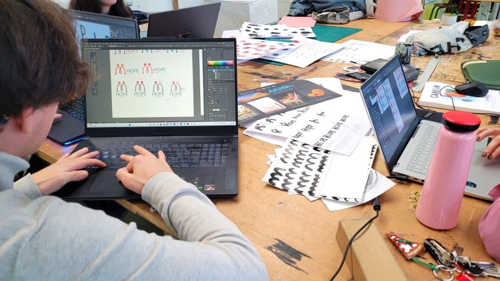 Étudiant sur son ordinateur portable en trian de réaliser un logo et une charte graphique.