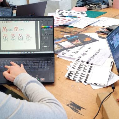 Étudiant sur son ordinateur portable en trian de réaliser un logo et une charte graphique.