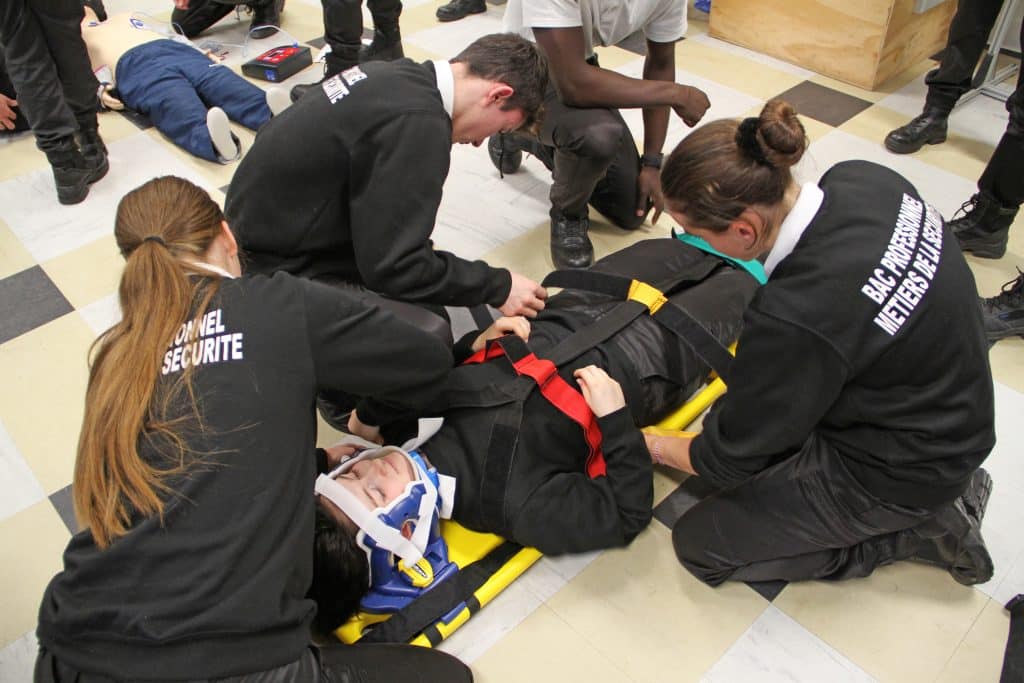 Lycéens en bac professionnel métiers de la sécurité en train d'apprendre à porter secours à une personne blessée.
