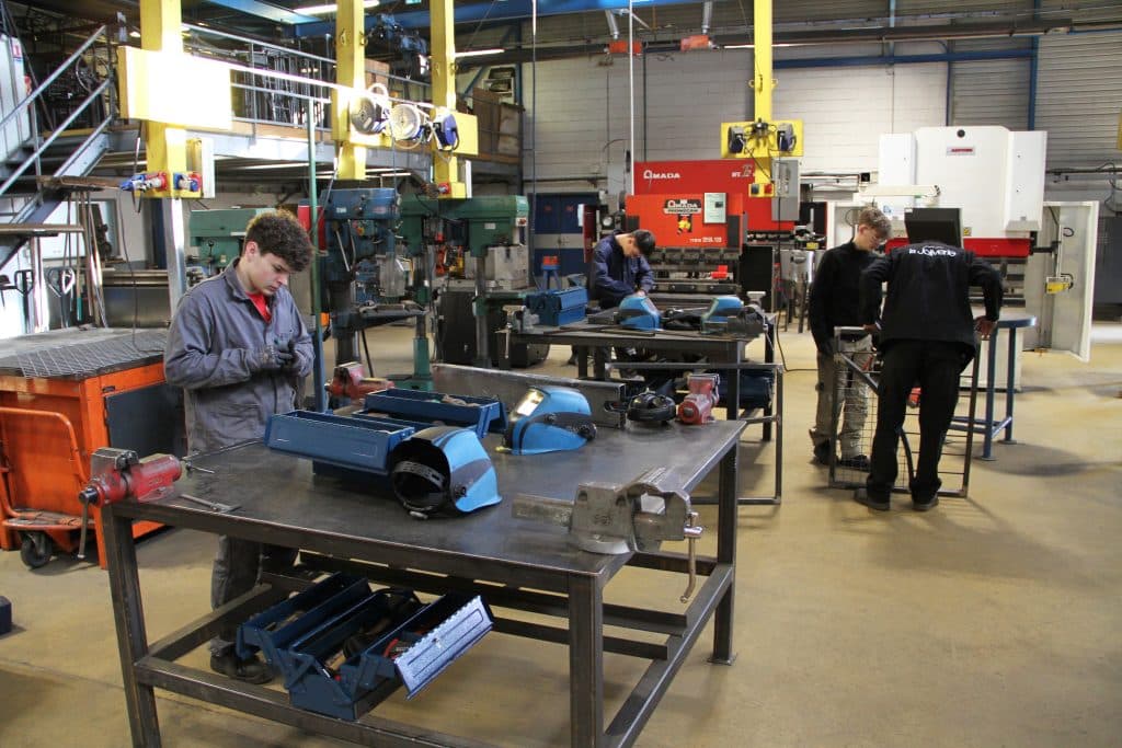 Atelier avec des élèves qui travaillent le métal.