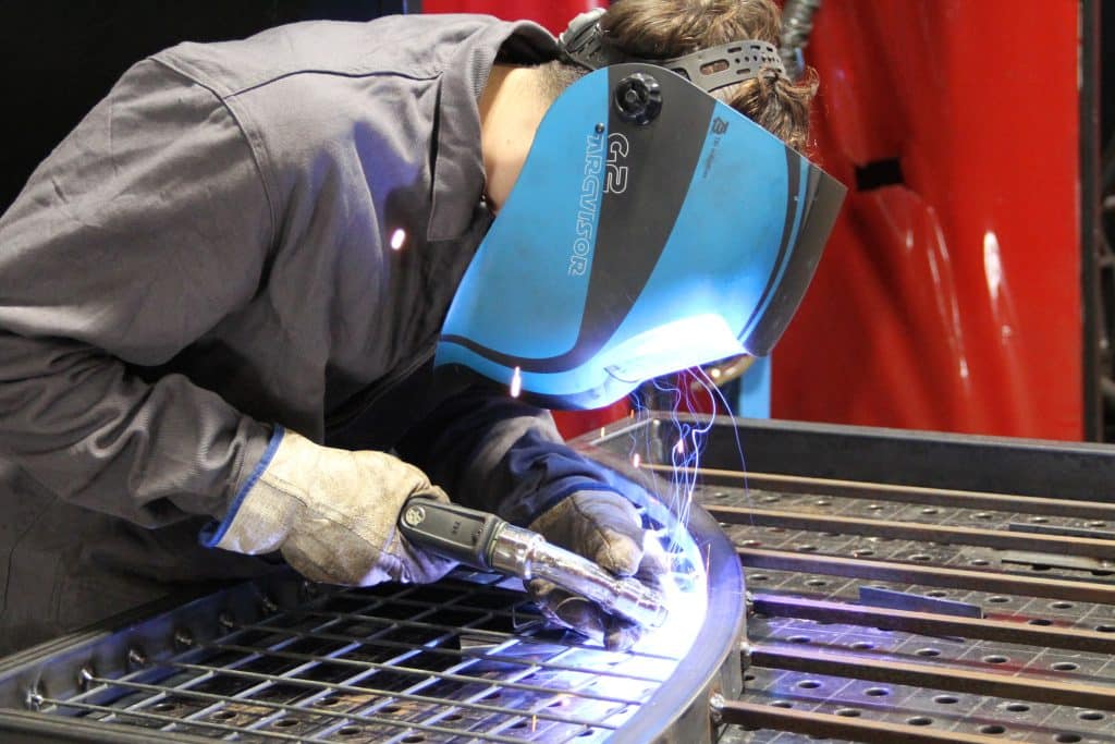 Un lycéen en train de réaliser une soudure avec un casque devant le visage.