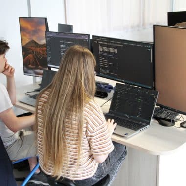 2 étudiants qui travaillent devant plusieurs écran dans une salle informatique de la Joliverie.