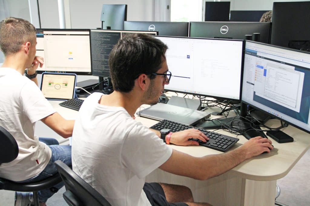 2 étudiants en train de travailler sur plusieurs écrans dans une salle informatique.