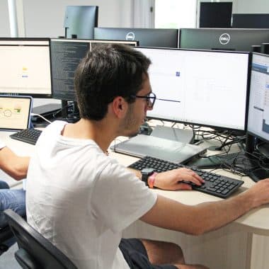 2 étudiants en train de travailler sur plusieurs écrans dans une salle informatique.