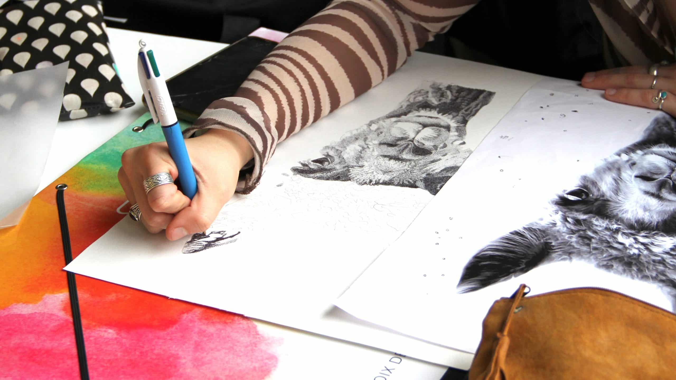 Élève en train de dessiner sur une feuille avec ses crayons.